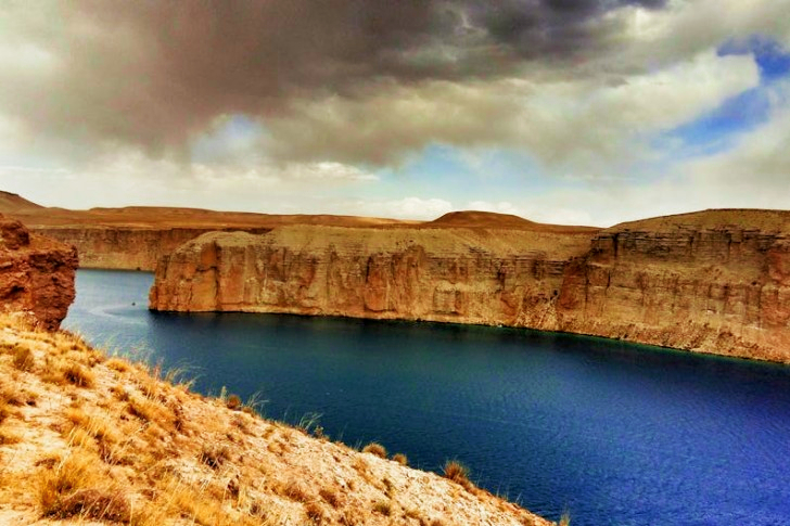 Body Of Water Surrounded By Rock Formation Under Cloudy Sky
