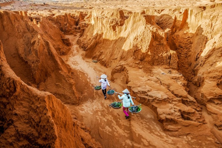 Agricultores caminhando pelas dunas de areia vermelha no Vietnã