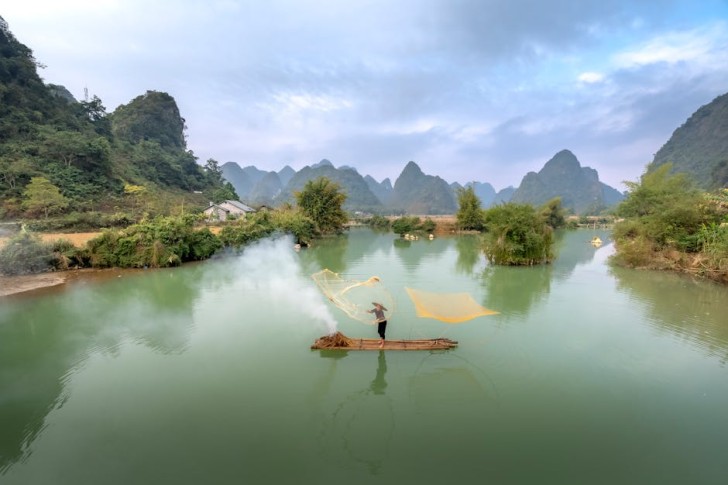 Kalastaja heittää verkkoja rauhallisella joella aamunkoitteessa