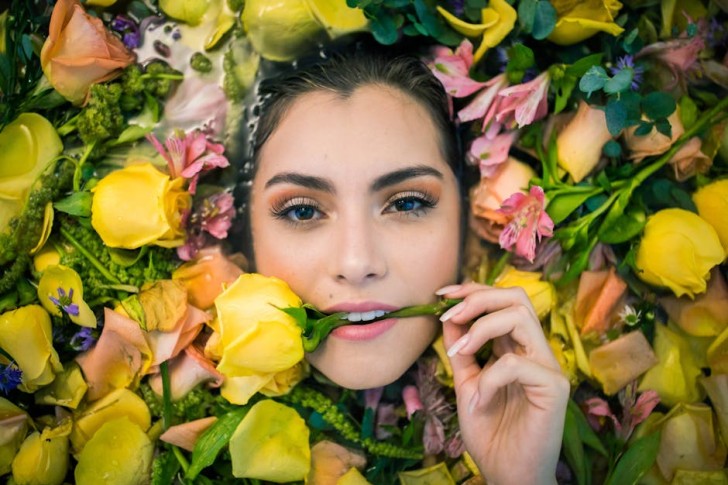 Retrato de una mujer mordiendo una rosa amarilla