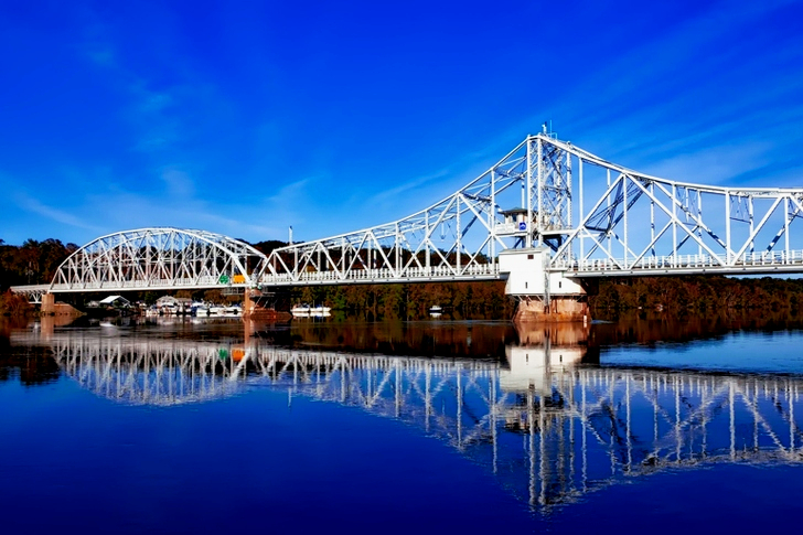 White Bridge Above Body of Water Creating a Reflection Under White Clouds