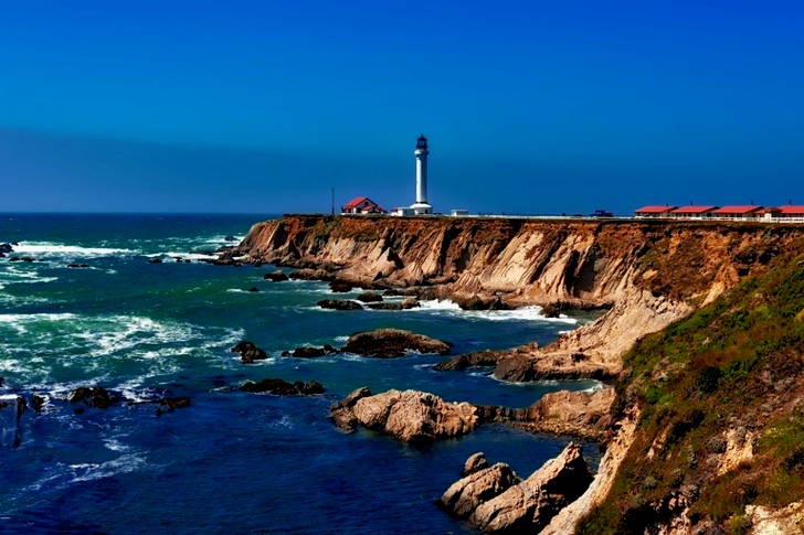 White Lighthouse Near Body of Water Under Blue Sky during Daytime