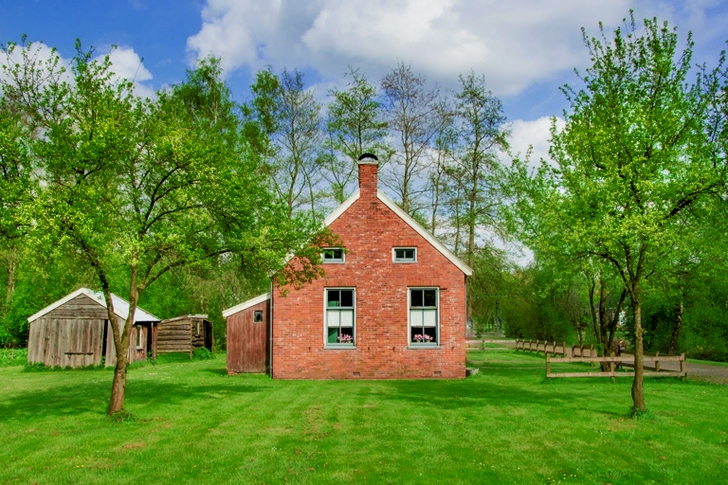 Brown Brick House Surrounded by Green Trees and Grass