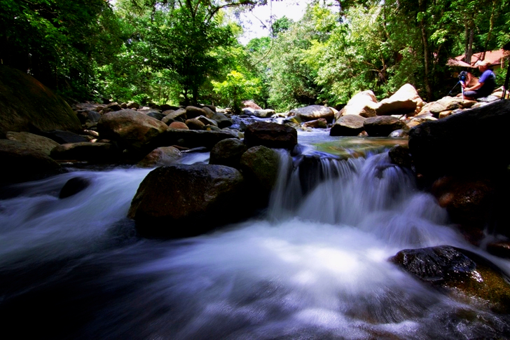Man Sitting on Rock Near the Waterfalls