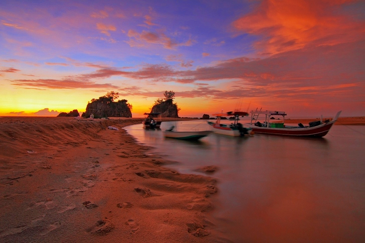 Witte boot aanmeren aan de kust tijdens zonsondergang