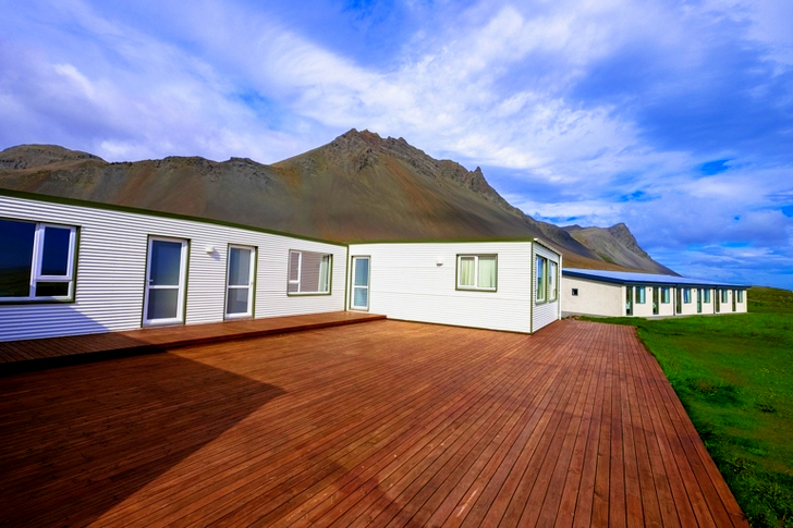 Mountain Across Houses on Green Grass Field Under Clear Blue Sky