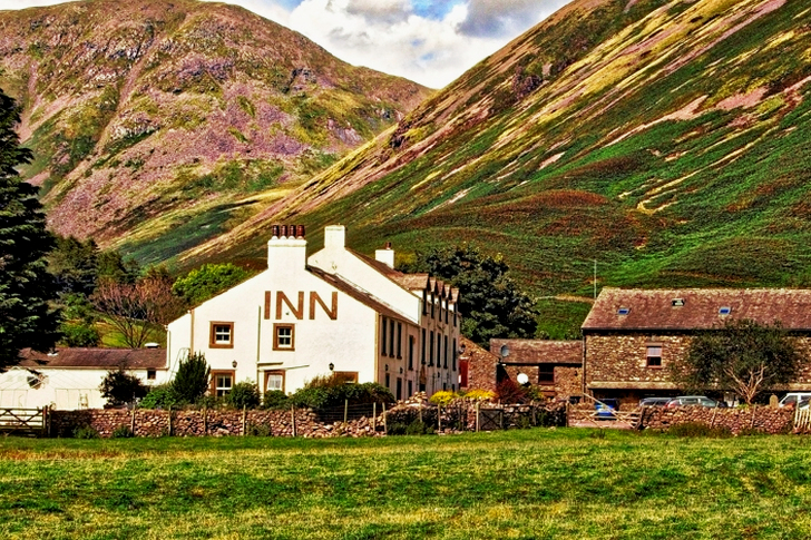 White Concrete Inn Near Green Covered Mountain at Daytime