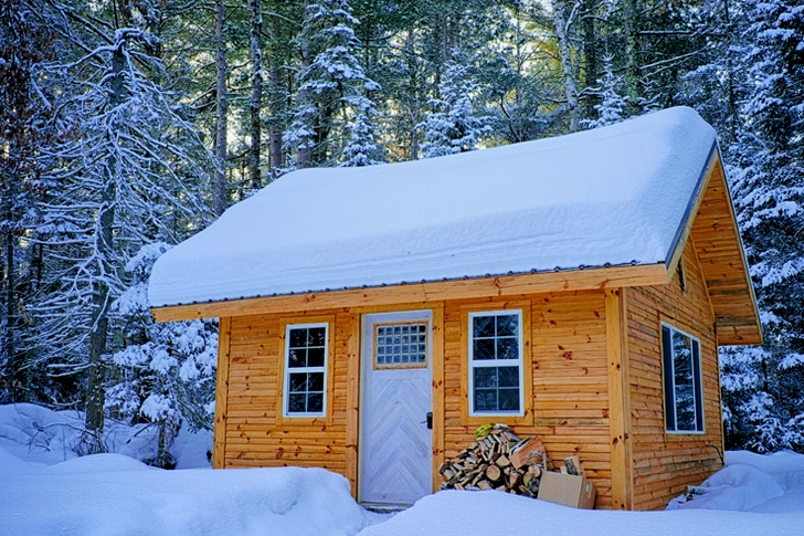 Snødekket trehus inne i skogen