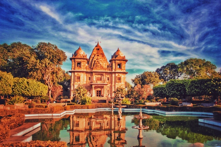 Brown Concrete Building Near Fountain Under Blue and Gray Sky