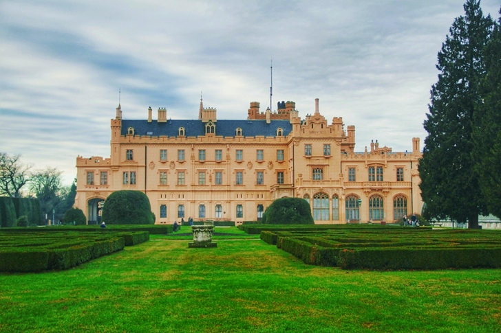 Beigefarbenes Betongebäude mit Buschlabyrinthfeld bei Tag