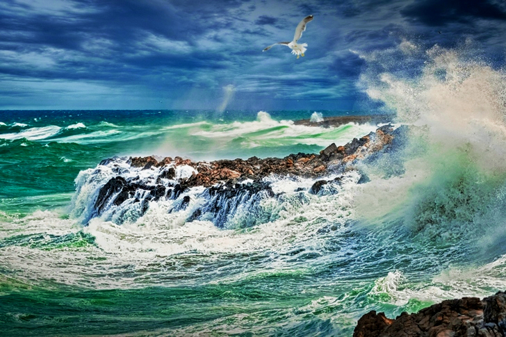 Beach Beside Stone Formation With Waves at Daytime
