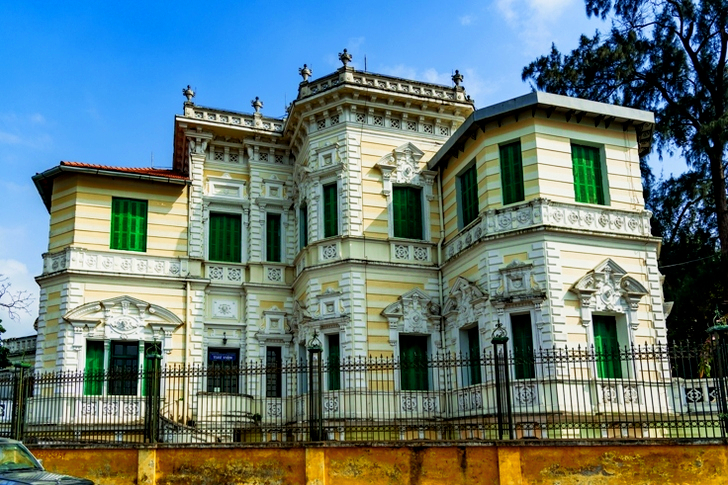 Yellow and White Painted Mansion Near Black Iron Gate