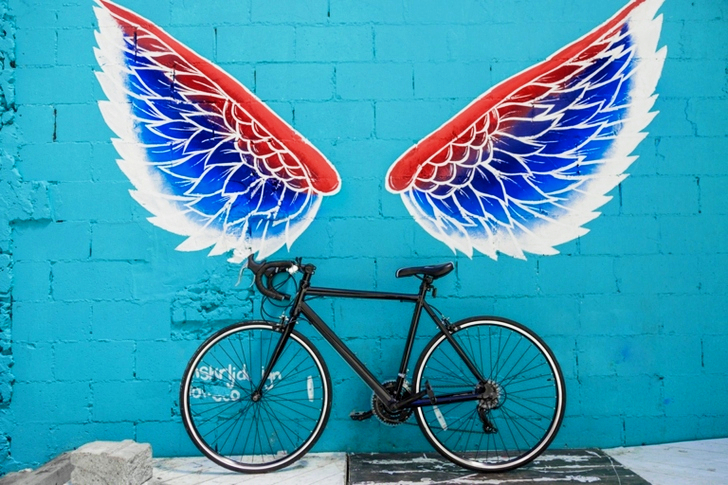 Black Road Bike Leaning on Red-blue-and-white Wing Graffiti Wall