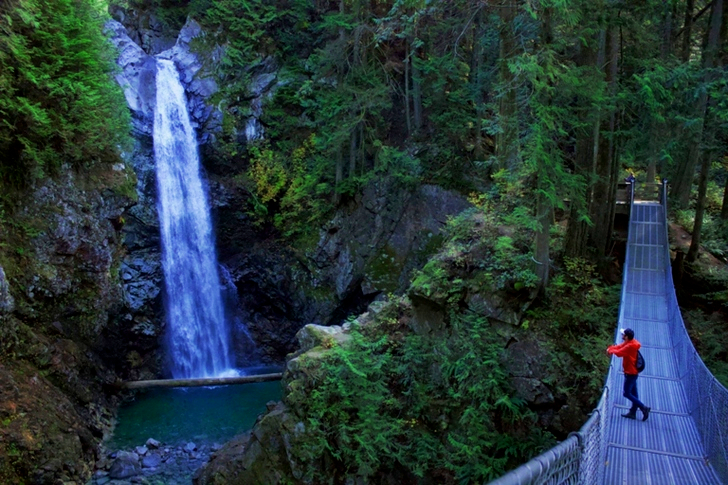 Man Standing on Hanging Bridge Looking at Waterfalls