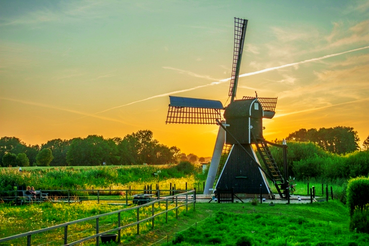 Black and White Wind Mill in Green Field Under Yellow Skies