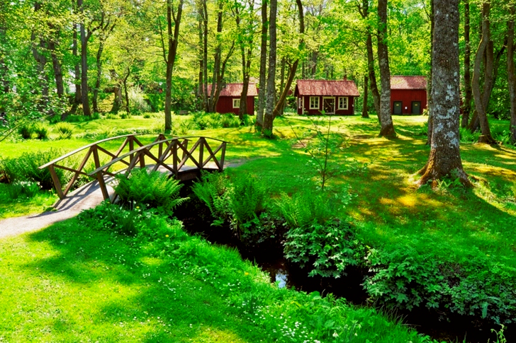 Brown Wooden House Near the Creek With a Bridge