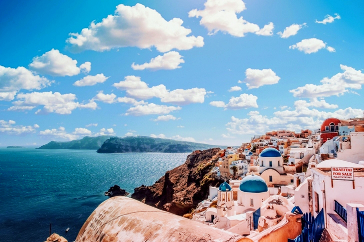 White Concrete House Near Body of Water Under White and Blue Cloudy Sky