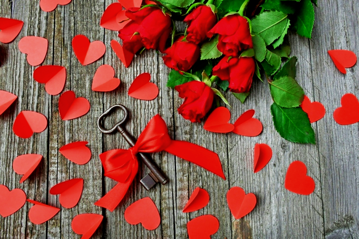 Black Metal Skeleton Key Beside Red Roses Bouquet on Gray Surface